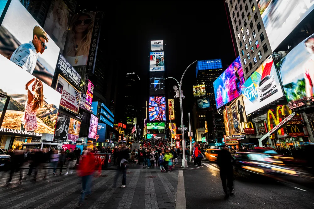 Illuminated Billboards And City Crowds In Times Square At Night.